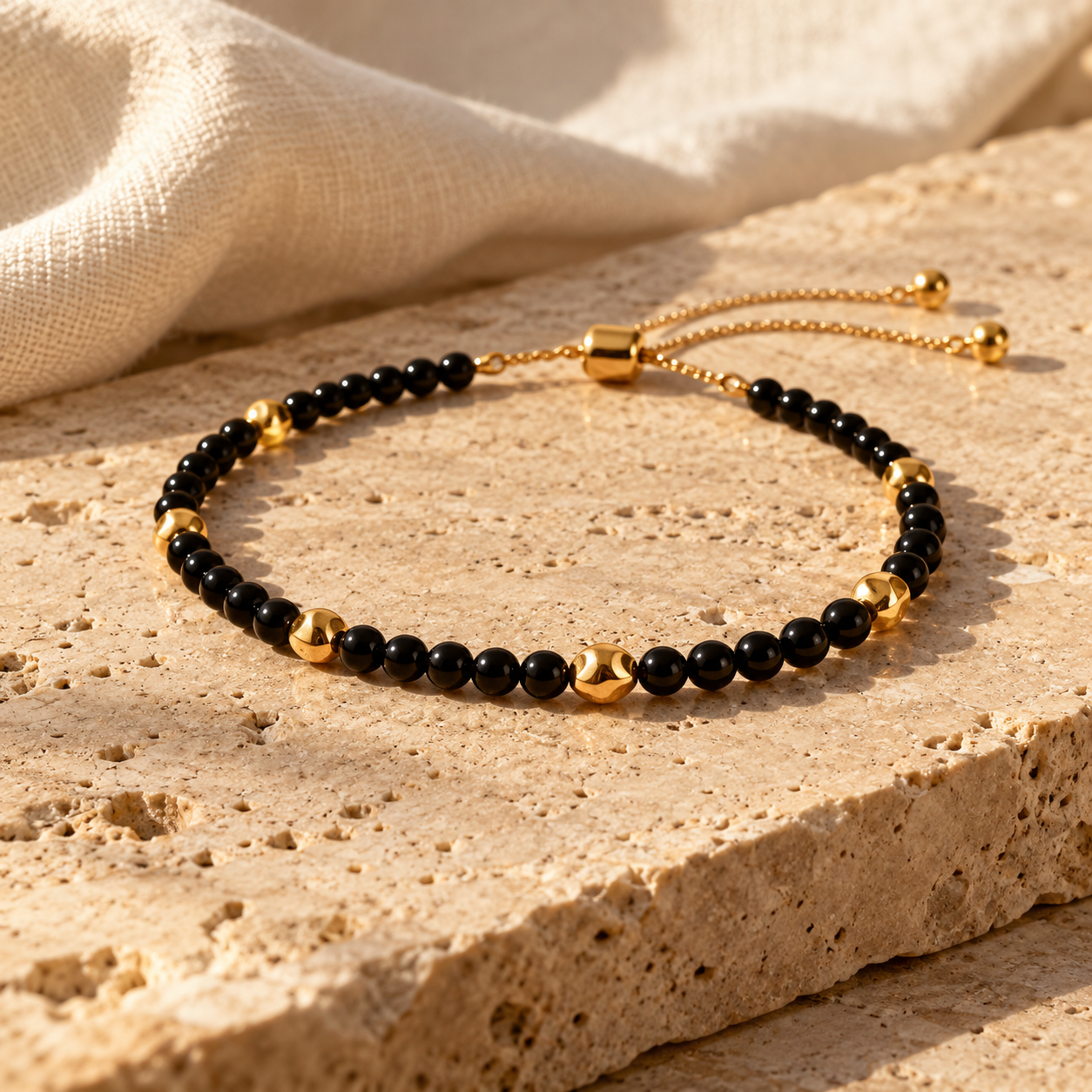 Kena bracelet of polished black onyx beads with scattered gold spacers